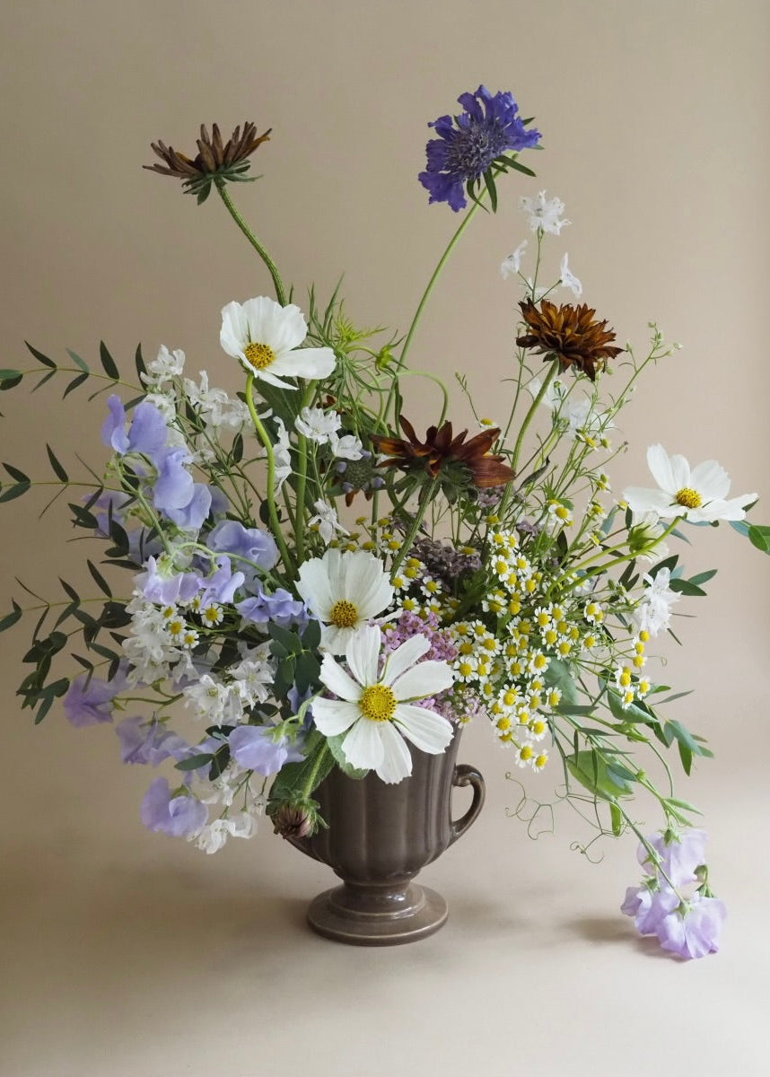 Floral arrangement in a brown vase on a beige background
